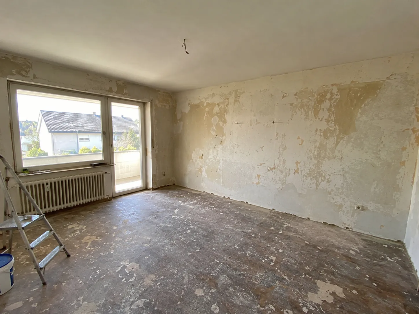 Vorher: Zimmer mit fleckigen, teils abgelösten Tapeten und abgenutztem Boden